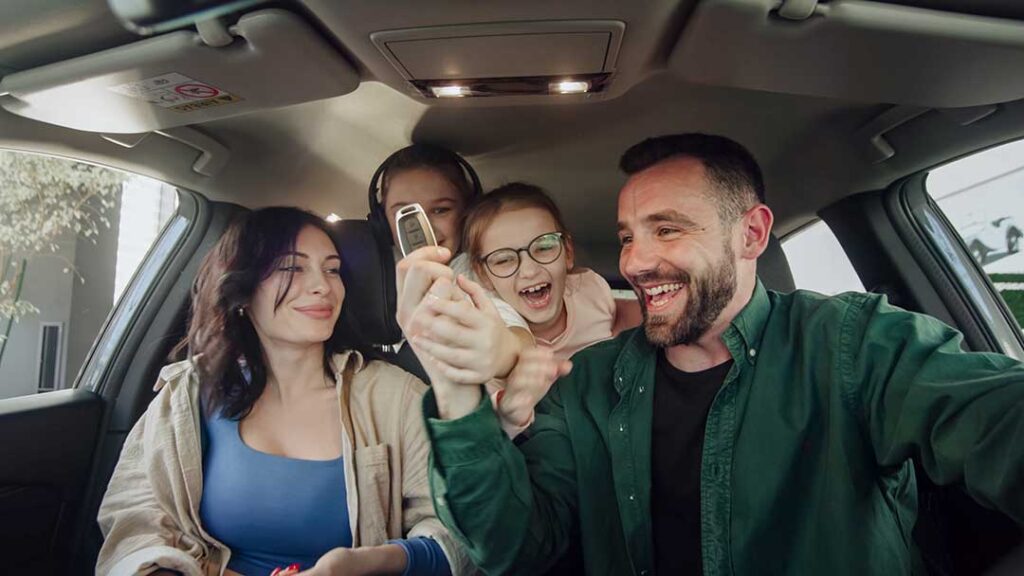 A family exploring the interior of a mid-sized SUV in a residential driveway.