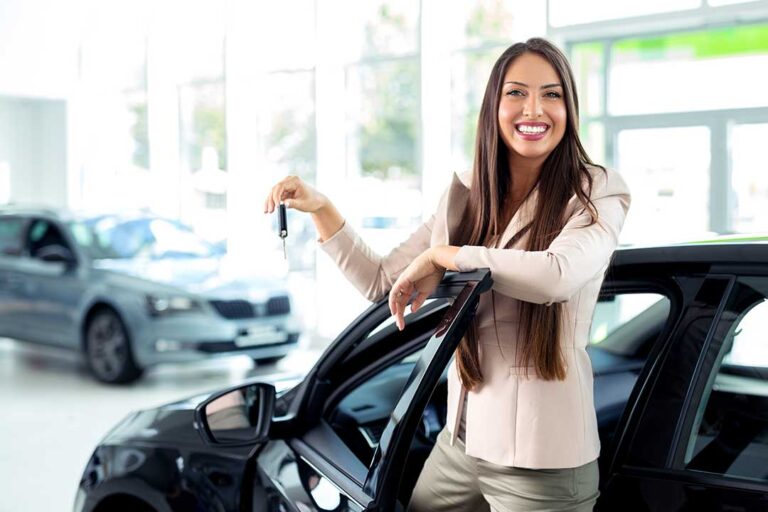A couple reviews an auto loan agreement at a table beside a vehicle, with payment figures and documents visible.
