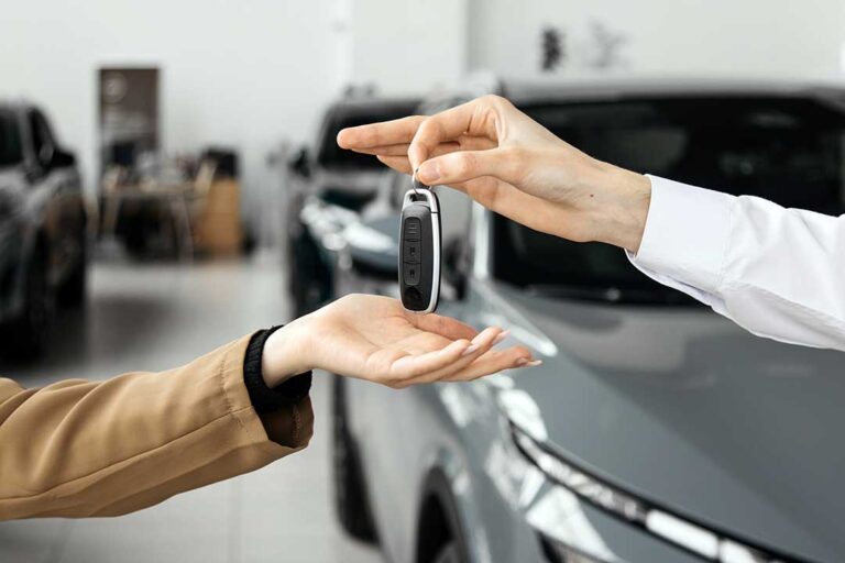 A buyer examines a vehicle window sticker through the side glass while comparing listed features and prices.